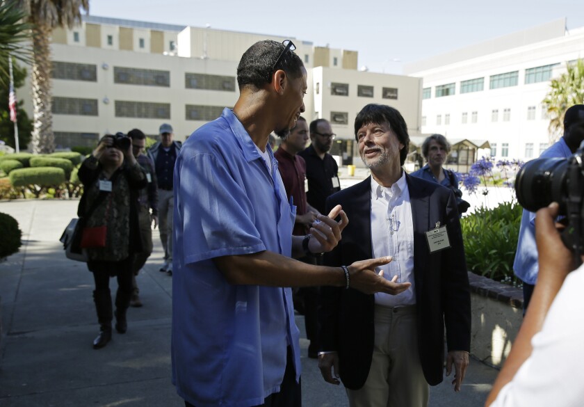 FILE - In this Wednesday, July 24, 2019, file photo, filmmaker Ken Burns walks with inmate Rahsaan Thomas at San Quentin State Prison in San Quentin, Calif. Burns visited the prison to show parts of his new documentary, Country Music. On Thursday, Jan. 13, 2022, Gov. Gavin Newsom commuted Thomas' sentence that will allowing him to immediately go before the state parole board which will decide if he should be released on parole. Thomas was serving a 55 1/2 years-to-life sentence for a 2000 second-degree murder conviction. (AP Photo/Eric Risberg, File)