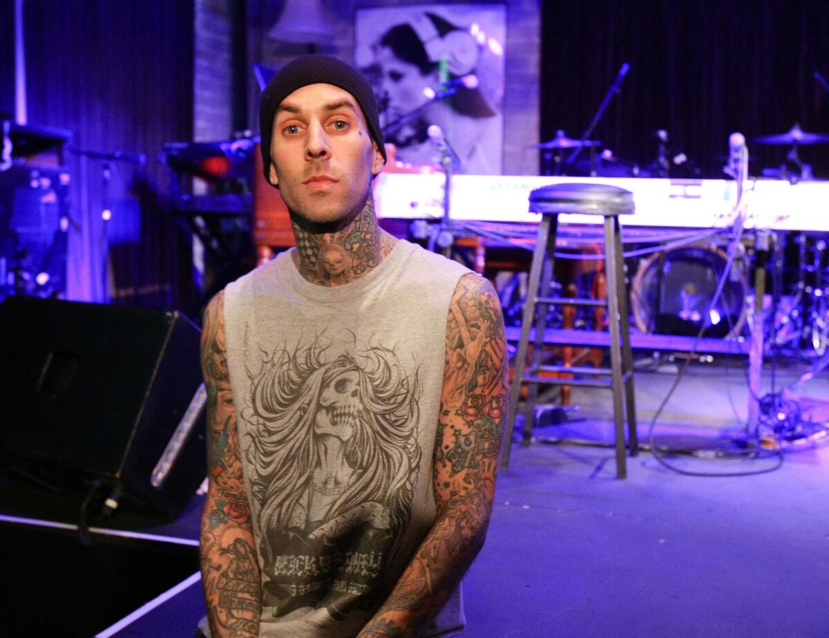 Travis Barker on stage in a tank top and a beanie
