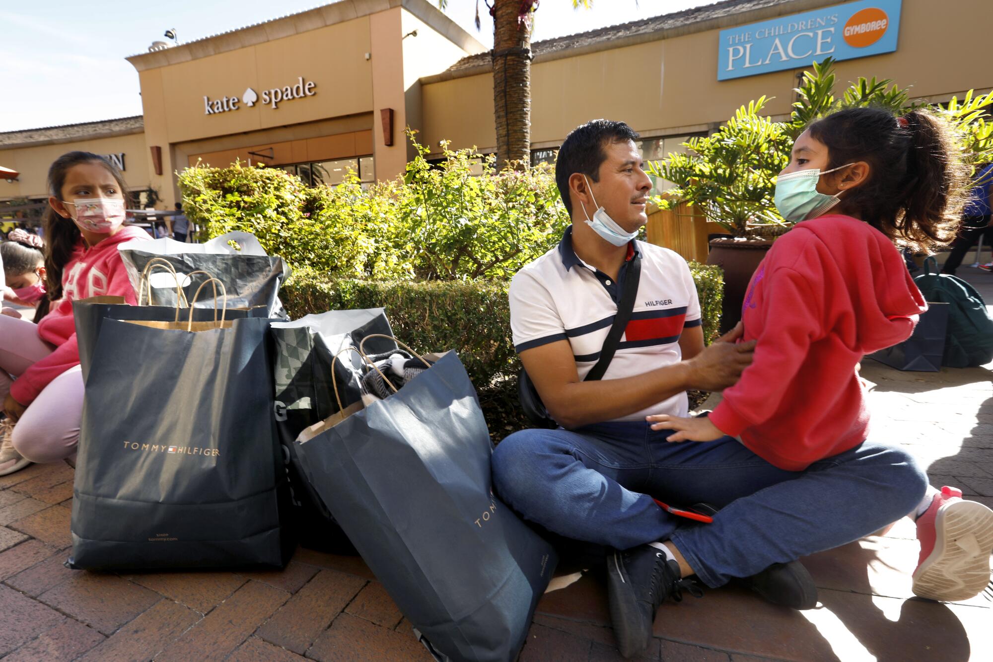 With their slew of shopping bags, Juan Vasquez, of Guadalajara, Mexico, and his family take a break at the Citadel Outlets