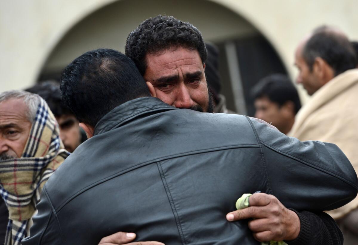 Pakistanis comfort each other as they gather to receive the bodies of suicide bomb attack victims outside a hospital in Islamabad on Monday.