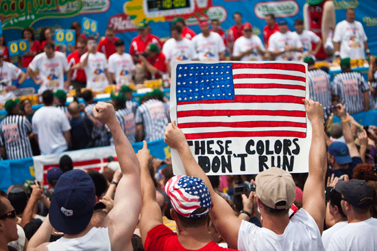 A man holds an American flag poster during the 2011 Nathan's Famous Fourth of July International Hot Dog Eating Contest.