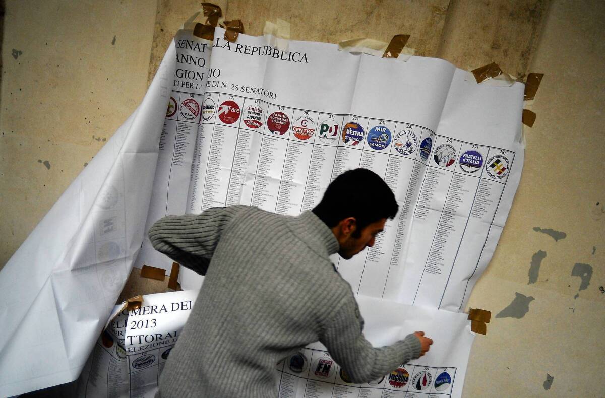 A worker takes down an electoral information banner at a polling station in downtown Rome.