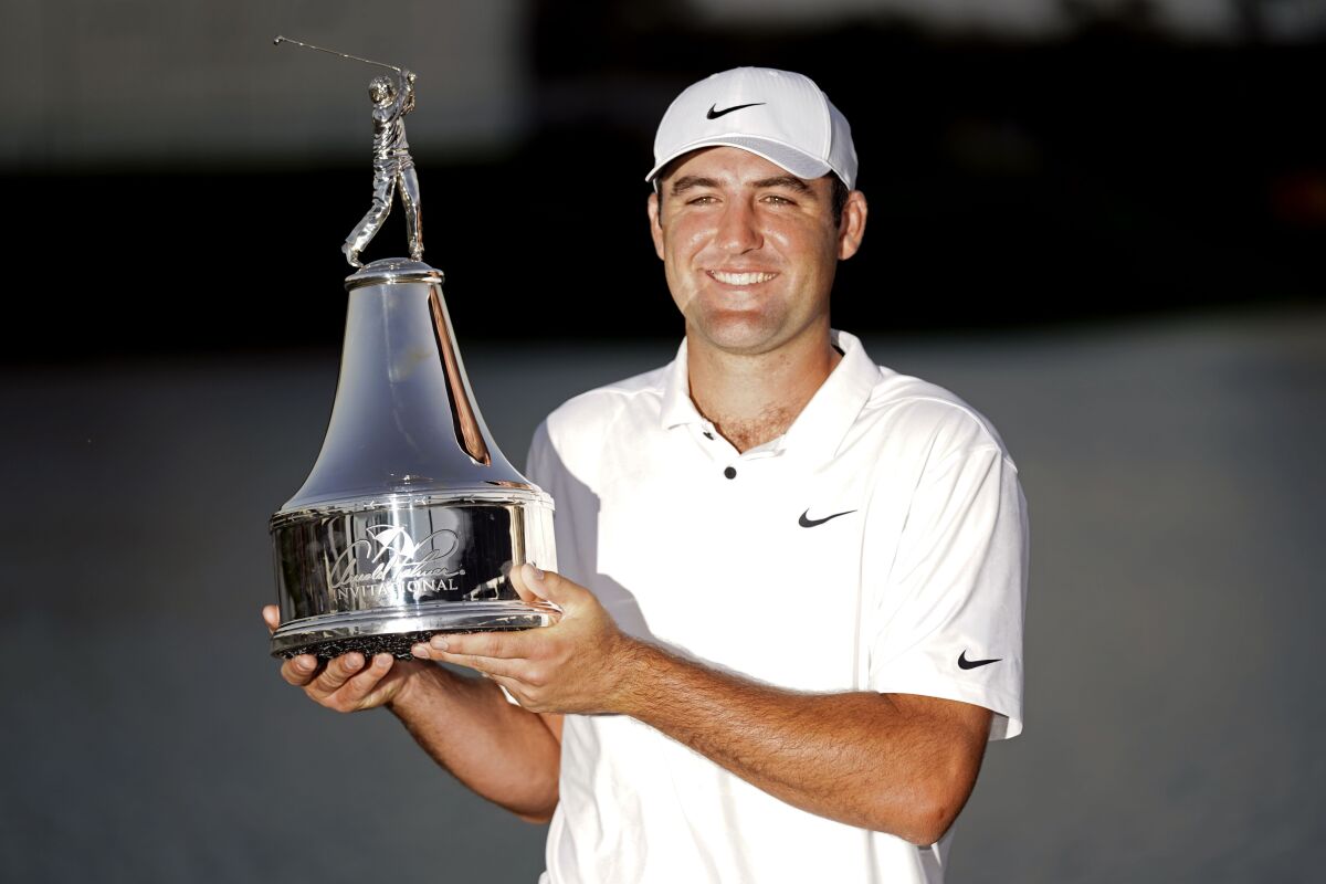 Scottie Scheffler holds up the championship trophy after winning 1the Arnold Palmer Invitational golf tournament Sunday, March 6, 2022, in Orlando, Fla. (AP Photo/John Raoux)