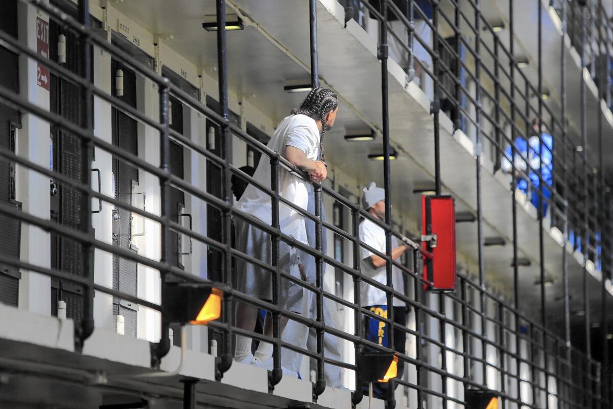 Men lean on the railing on a cellblock in prison