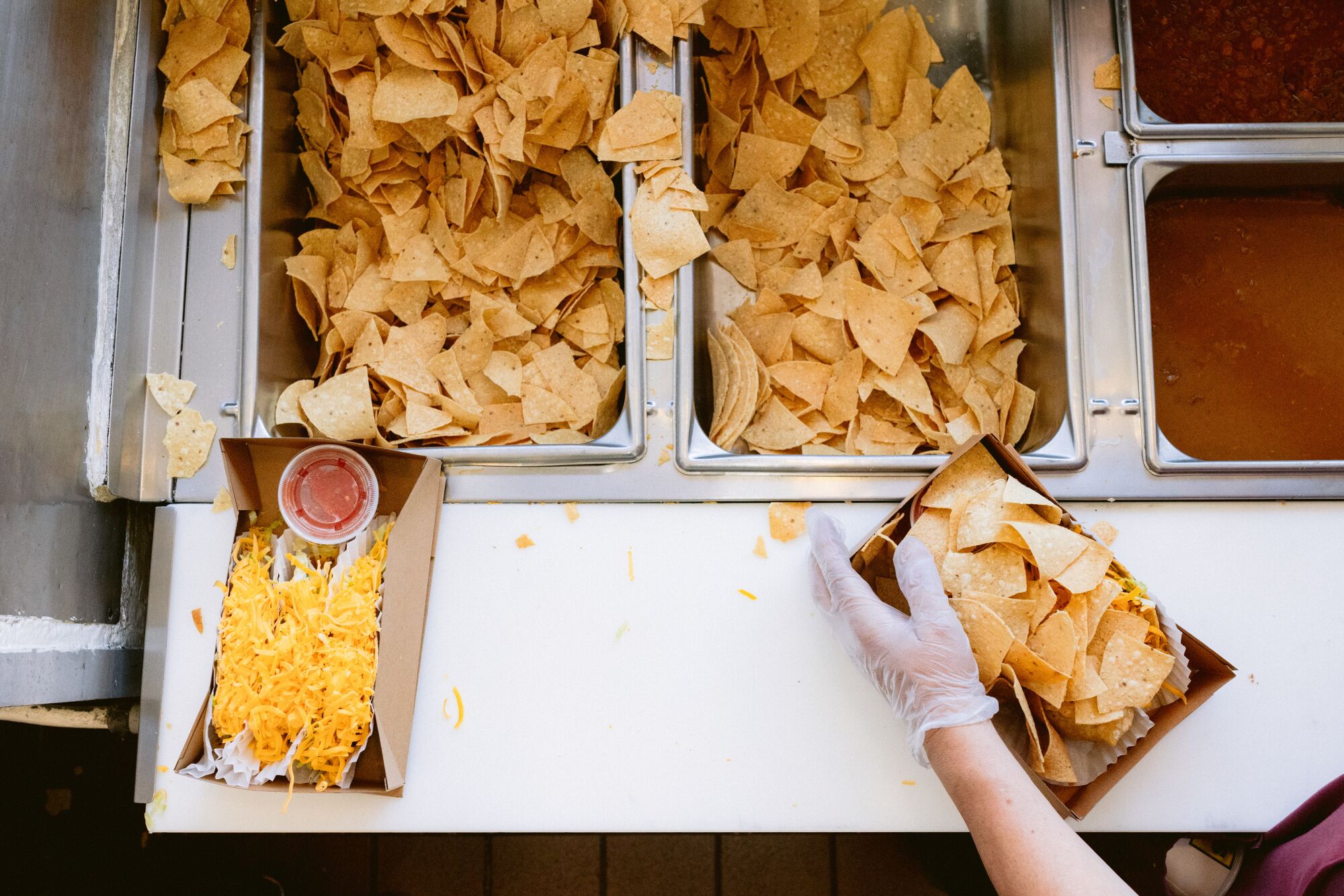 Overhead image of hands boxing up tacos and chips.