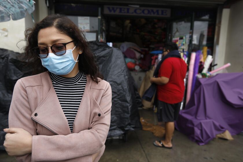 LOS ANGELES, CA - MARCH 10, 2020 - Charm Resuello, 26, wears a surgical mask to ward off Covid-19, while shopping for flowers in the Flower District in downtown Los Angeles on March 10, 2020. 'Being careful doesn't hurt you," said Resuello about wearing the mask while shopping. (Genaro Molina / Los Angeles Times)