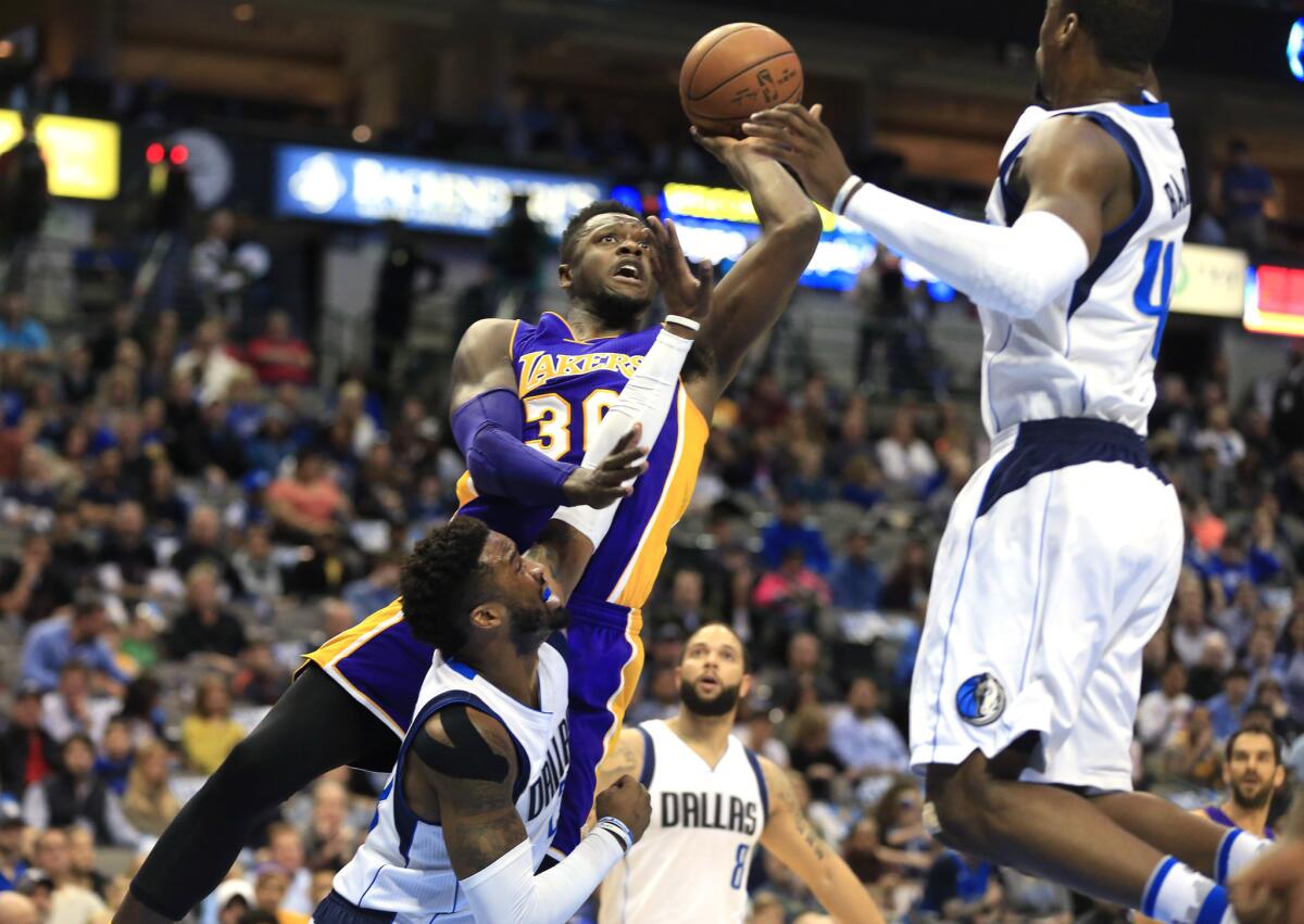 Lakers forward Julius Randle tries to score inside against Mavericks guard Wesley Matthews and forward Harrison Barnes, right, during the first half Sunday.