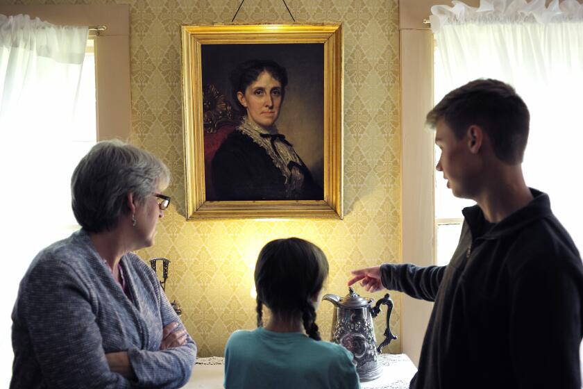 FILE - In this May 17, 2018 file photo, museum visitors stand near a portrait of author Louisa May Alcott by American artist George Healy at Orchard House in Concord, Mass. The current issue of The Strand Magazine will give readers the chance to discover an obscure and unfinished work of fiction by Alcott, "Aunt Nellie's Diary," and to provide a conclusion themselves. Guidelines will be announced in the coming weeks. (AP Photo/Steven Senne, File)