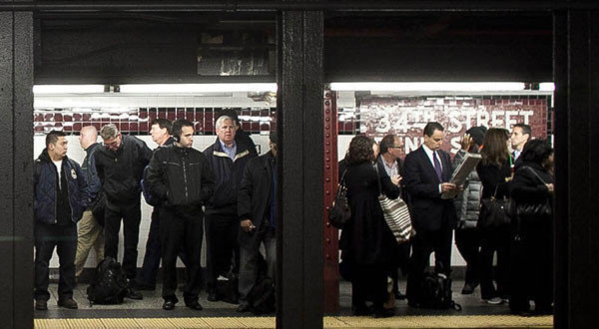 Commuters wait for the A train at Penn Station in New York.