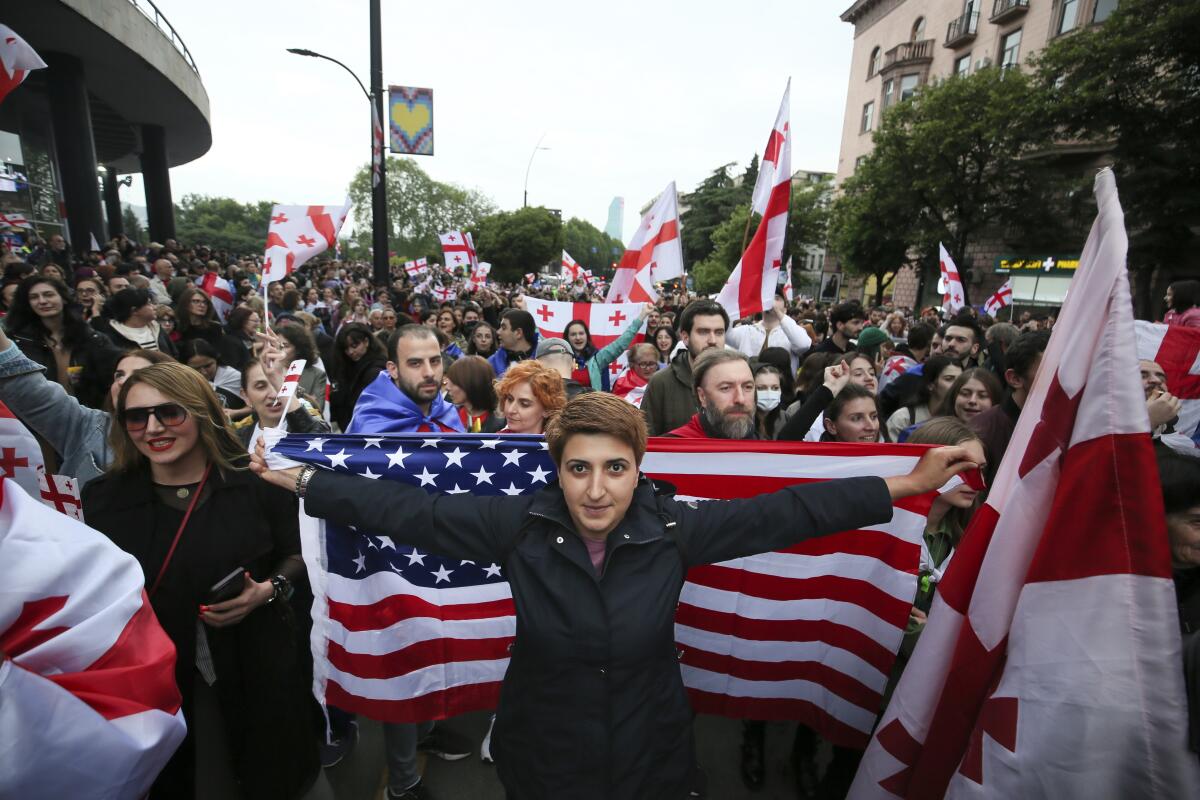Demonstrators with Georgian national US flags rally during an opposition protest against foreign influence bill and celebrating of the Independence Day in the center of in Tbilisi, Georgia, Sunday, May 26, 2024. The opposition has denounced the bill as "the Russian law," because Moscow uses similar legislation to crack down on independent news media, nonprofits and activists critical of the Kremlin. (AP Photo/Zurab Tsertsvadze)