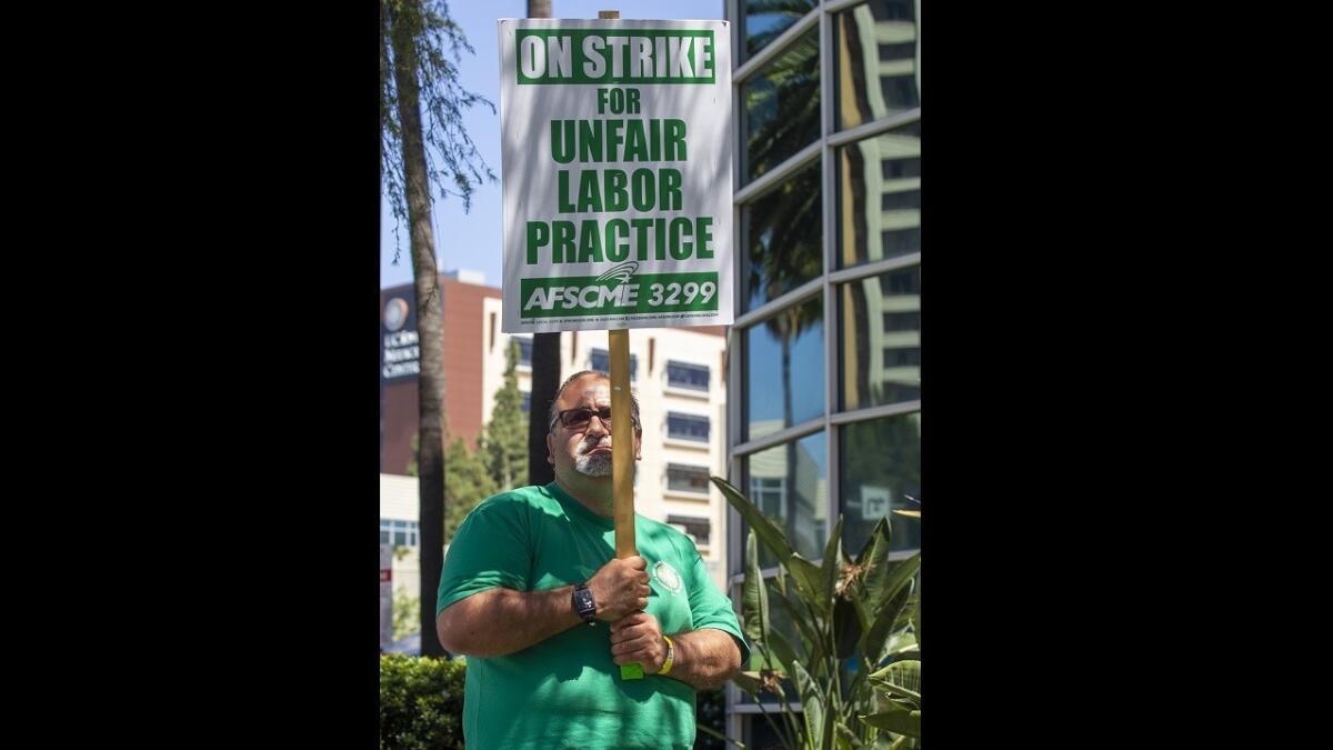 Vicente Chavez, a custodian at UC Irvine Medical Center, holds a sign while on the picket line Wednesday.