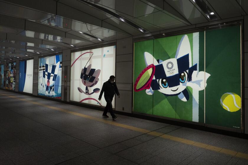 Un individuo pasa frente a imágenes de promoción de los Juegos Olímpicos de Tokio 2020 en Tokio, el martes 24 de marzo de 2020. El COI anunció que los Juegos han sido pospuestos hasta 2021. (AP Foto/Jae C. Hong)