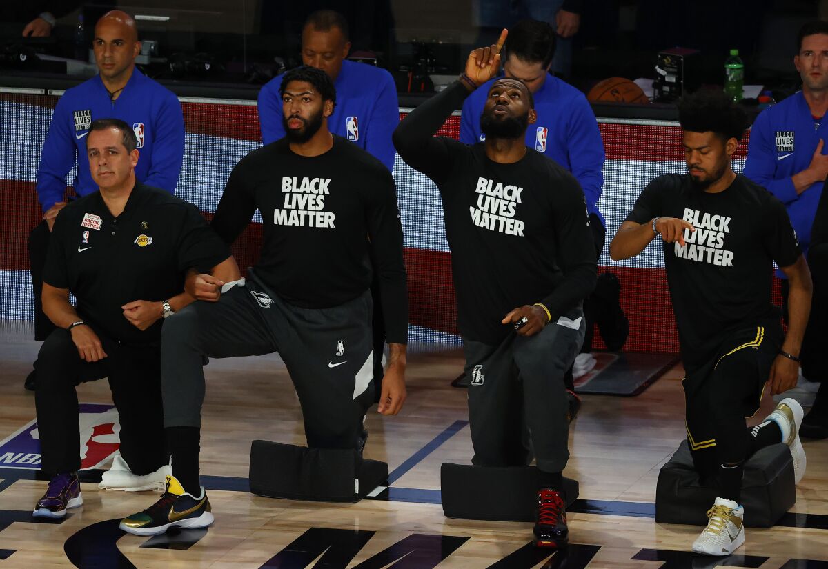 Lakers star LeBron James, second from right, points skyward during the national anthem.