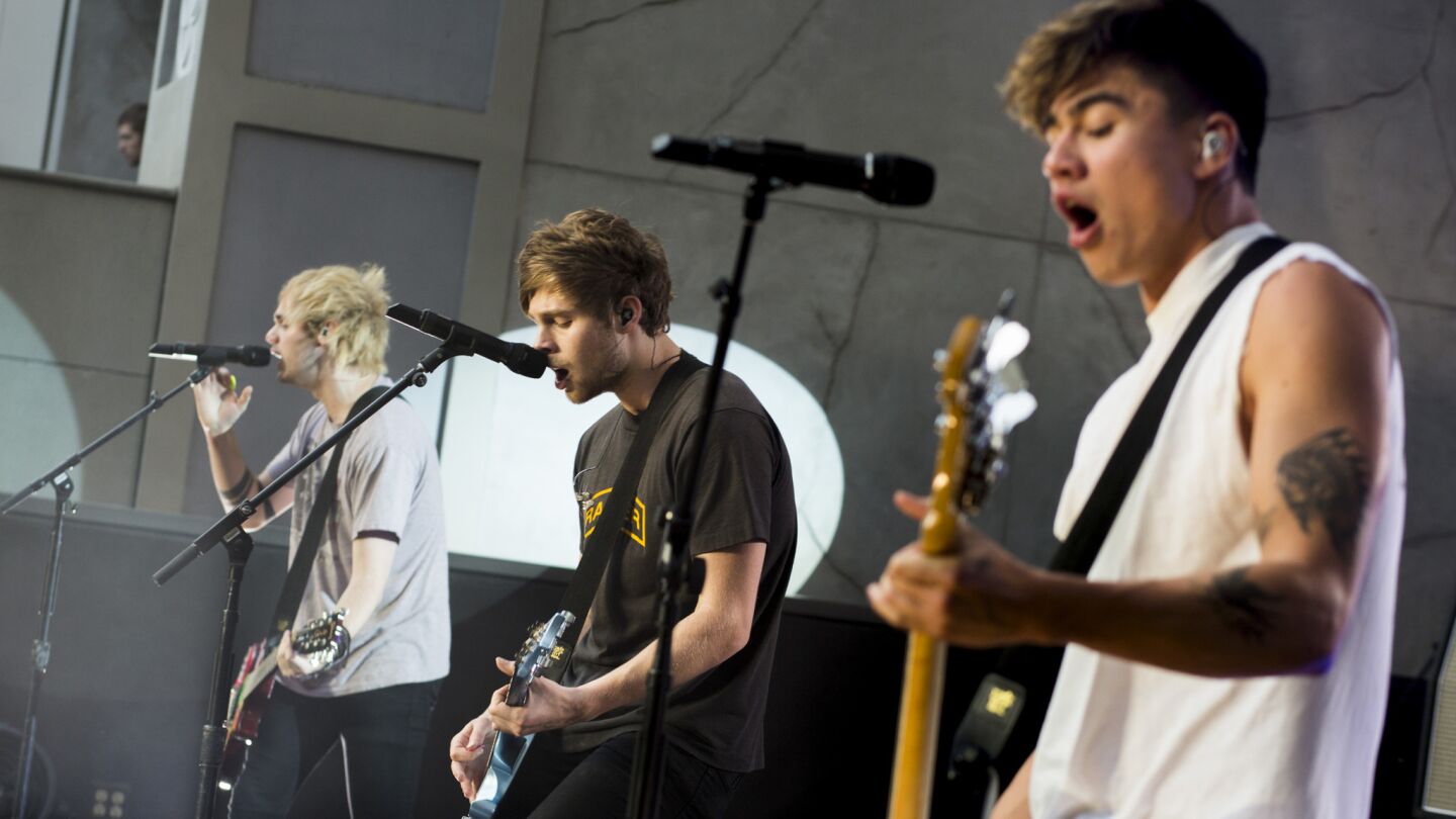 Australian pop band 5 Seconds of Summer members Michael Clifford, left, Luke Hemmings and Calum Hood perform at Hollywood & Highland Center.