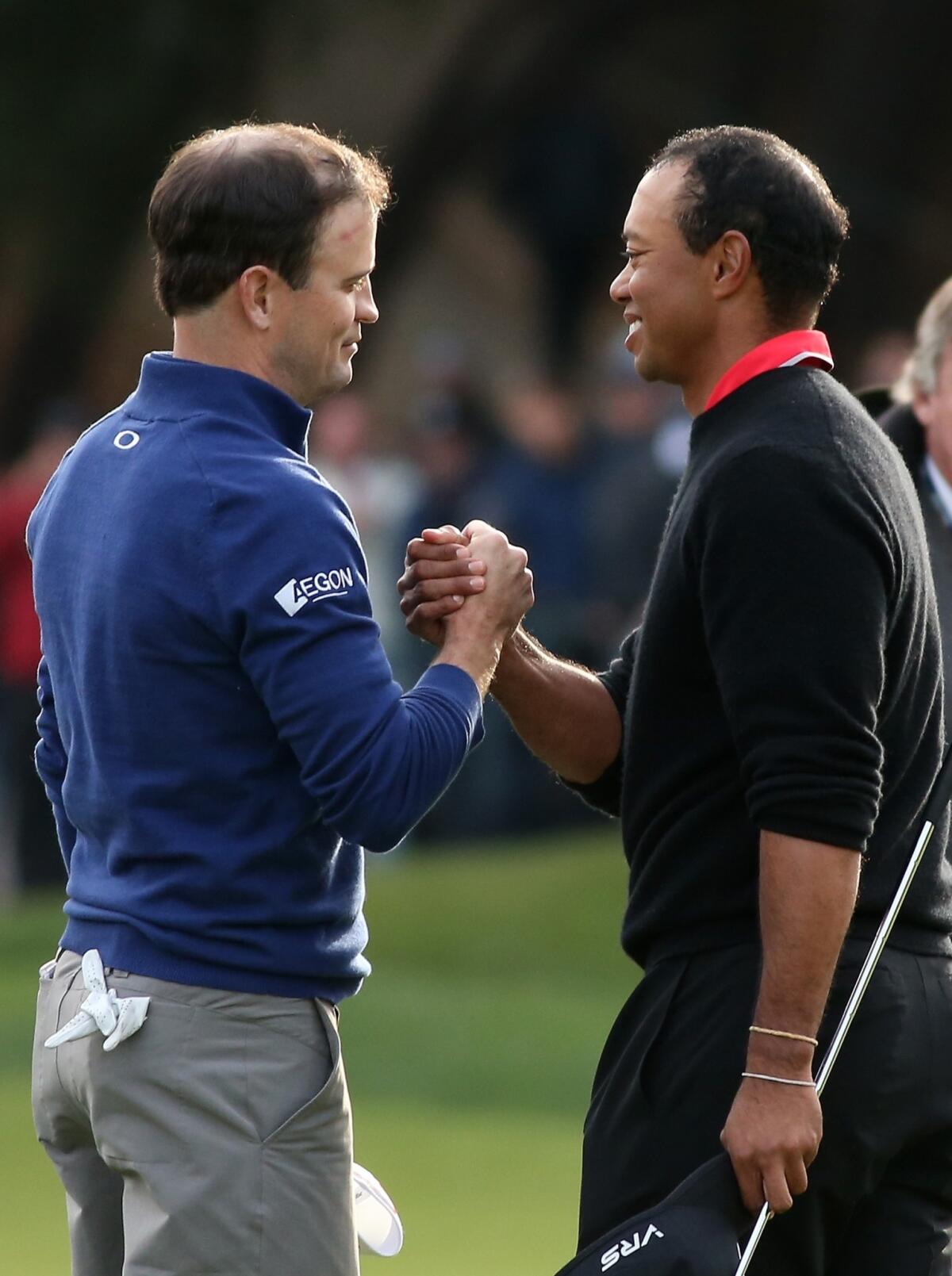 Zach Johnson, left, is congratulated by Tiger Woods after beating Woods on a playoff hole to win the Northwestern Mutual World Challenge at Sherwood Country Club in Thousand Oaks on Sunday.