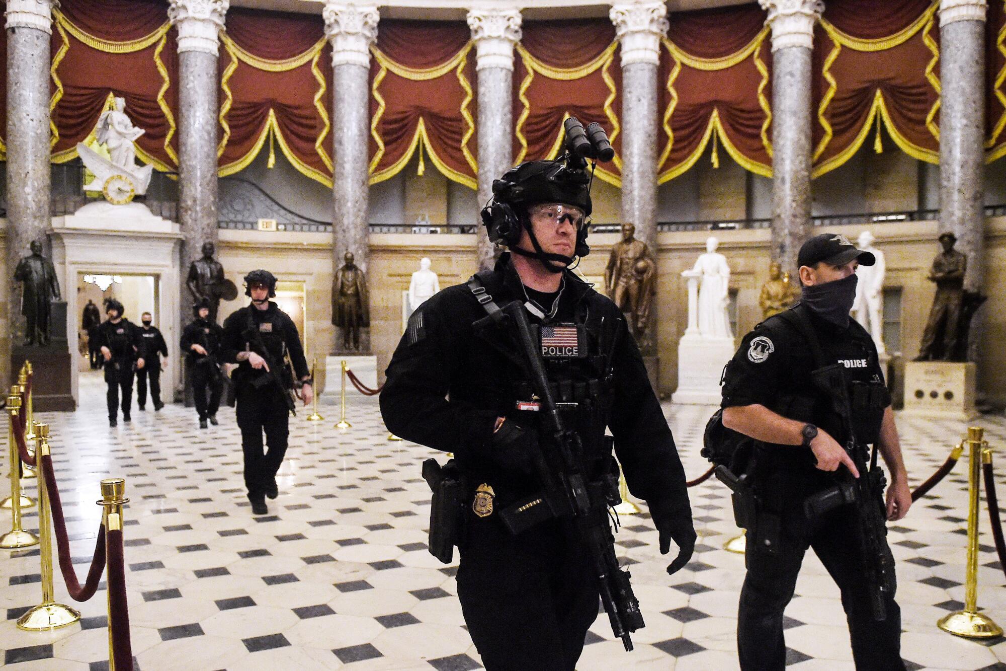 Law enforcement officers patrol the Statuary Hall of the Capitol.
