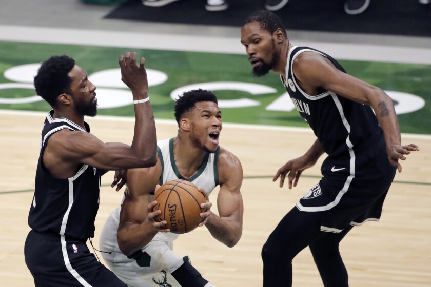 Milwaukee Bucks' Giannis Antetokounmpo, middle, drives to the basket between Brooklyn Nets' Jeff Green, left, and Kevin Durant, right, during the first half of an NBA basketball game Tuesday, May 4, 2021, in Milwaukee. (AP Photo/Aaron Gash)