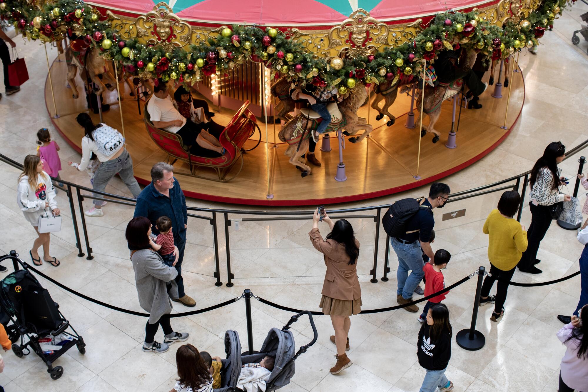 Patrons wait in line for a ride on the carousel on Black Friday at South Coast Plaza in Costa Mesa.
