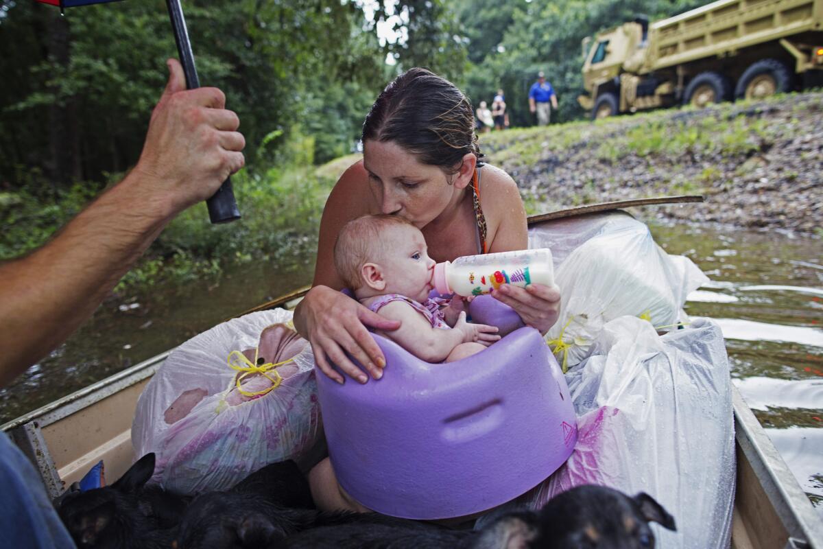 Danielle Blount besa a su hija de tres meses, Ember, mientras le da su biberón y esperan ambas a ser rescatadas por la Guardia Nacional cerca de Walker, Louisiana, donde las fuertes lluvias inundaron la región, el domingo 14 de agosto de 2016. (AP Foto/Max Becherer)