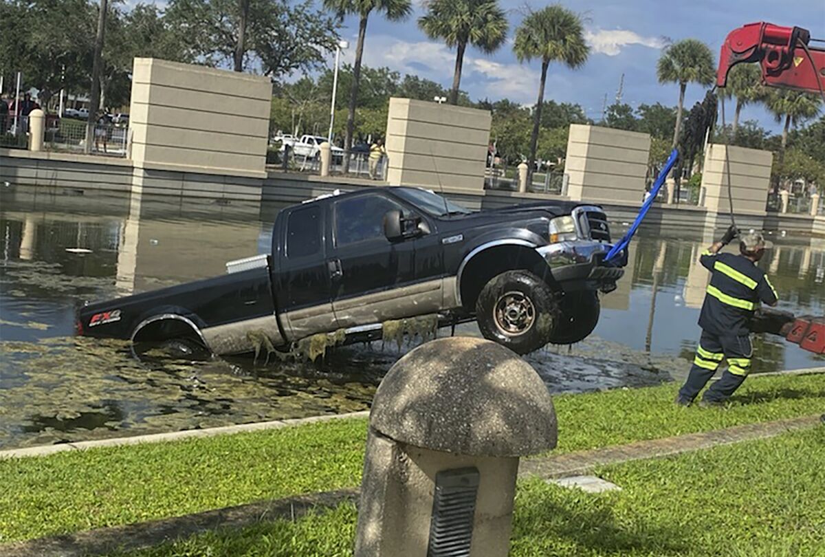 In this photo provided by the Florida Highway Patrol a vehicle is removed from a pond after it crashed outside the Pinellas County Justice Center, Wednesday, Sept. 2, 2020, in Clearwater, Fla. The 64-year-old driver was attempting to pull into a spot when his boot became entangled with the accelerator and vaulted into the retention pond, according to the Florida Highway Patrol. The truck became fully submerged, but deputies at the courthouse were able to help the man to safety. (Florida Highway Patrol via AP)