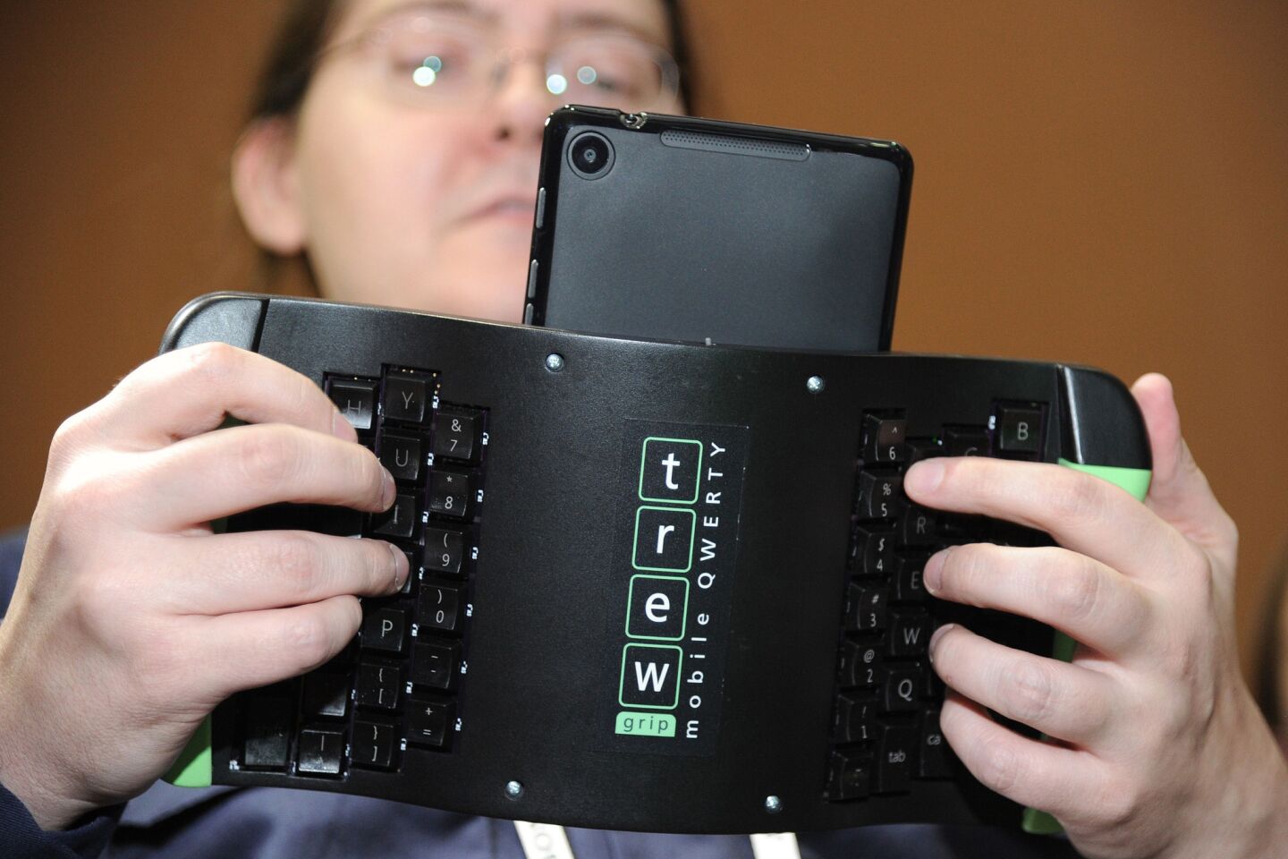 Robert Price of TREWGrip LLC demonstrates a TREWGrip handheld rear-type keyboard and air mouse for Apple and Android tablets at the "CES: Unveiled" media preview.