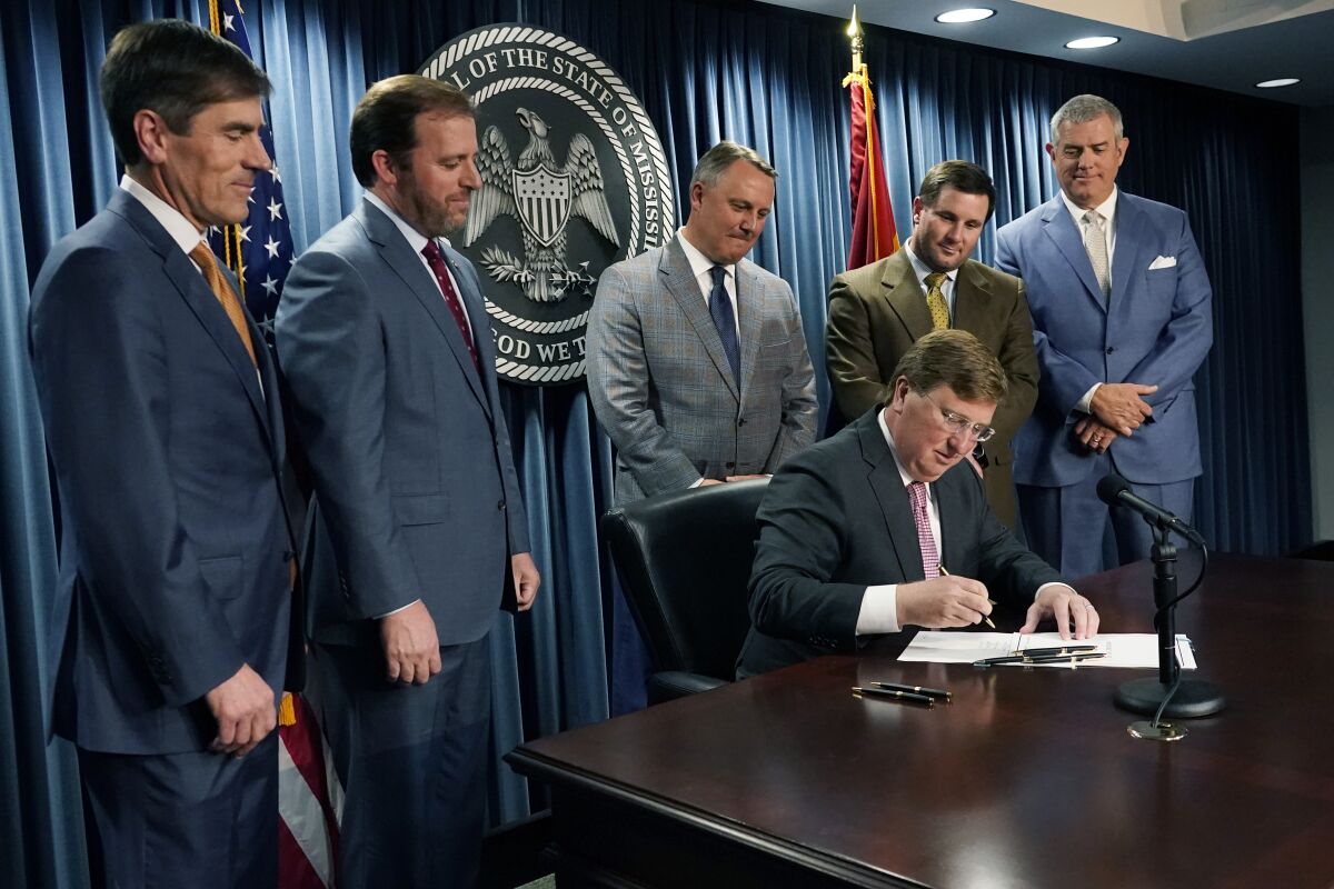 Republican Gov. Tate Reeves, seated, signs a bill that will reduce the state income tax over four years, beginning in 2023, at his office in Jackson, Miss., Tuesday, April 5, 2022. Attending the signing were from left, Senate Appropriations Committee Chairman Briggs Hopson, R-Vicksburg, Senate Finance Committee Chairman Josh Harkins, R-Flowood, House Speaker Pro Tempore Jason White, R-West, House Ways and Means Committee Chairman Trey Lamar, R-Senatobia and House Speaker Philip Gunn, R-Clinton. (AP Photo/Rogelio V. Solis)