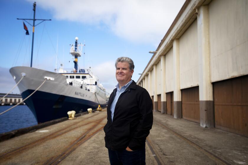 SAN PERDO, CA - NOVEMBER 06: Portrait of Tim McOsker, AltaSea Chief Executive Officer as he is standing between the Nautilus, a research vessel and the early 20th century warehouse on Friday, Nov. 6, 2020 in San Perdo, CA. There are two major projects in the vicinity of the original Port of Los Angeles in San Pedro they are moving ahead despite the pandemic. (Francine Orr / Los Angeles Times)