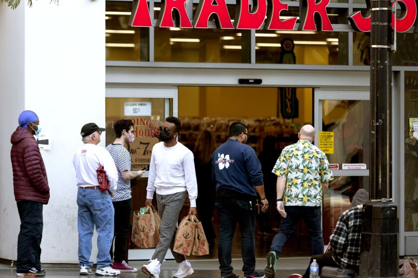 People stand in line, but leaving space to the neighboring person, while waiting to enter a Trader Joe's grocery store in the Hollywood section of Los Angeles on Tuesday, March 24, 2020. (AP Photo/Damian Dovarganes)