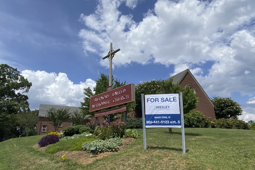 This photo provided by the Rev. Lucy Robbins shows a "For Sale" sign in front of the Biltmore United Methodist Church in Asheville, N.C. in July 2021. Already financially strapped because of shrinking membership and a struggling preschool, the congregation was dealt a crushing blow by the coronavirus. Attendance plummeted, with many staying home or switching to other churches that stayed open the whole time. Gone, too, is the revenue the church formerly got from renting its space for events and meetings. (Rev. Lucy Robbins via AP)