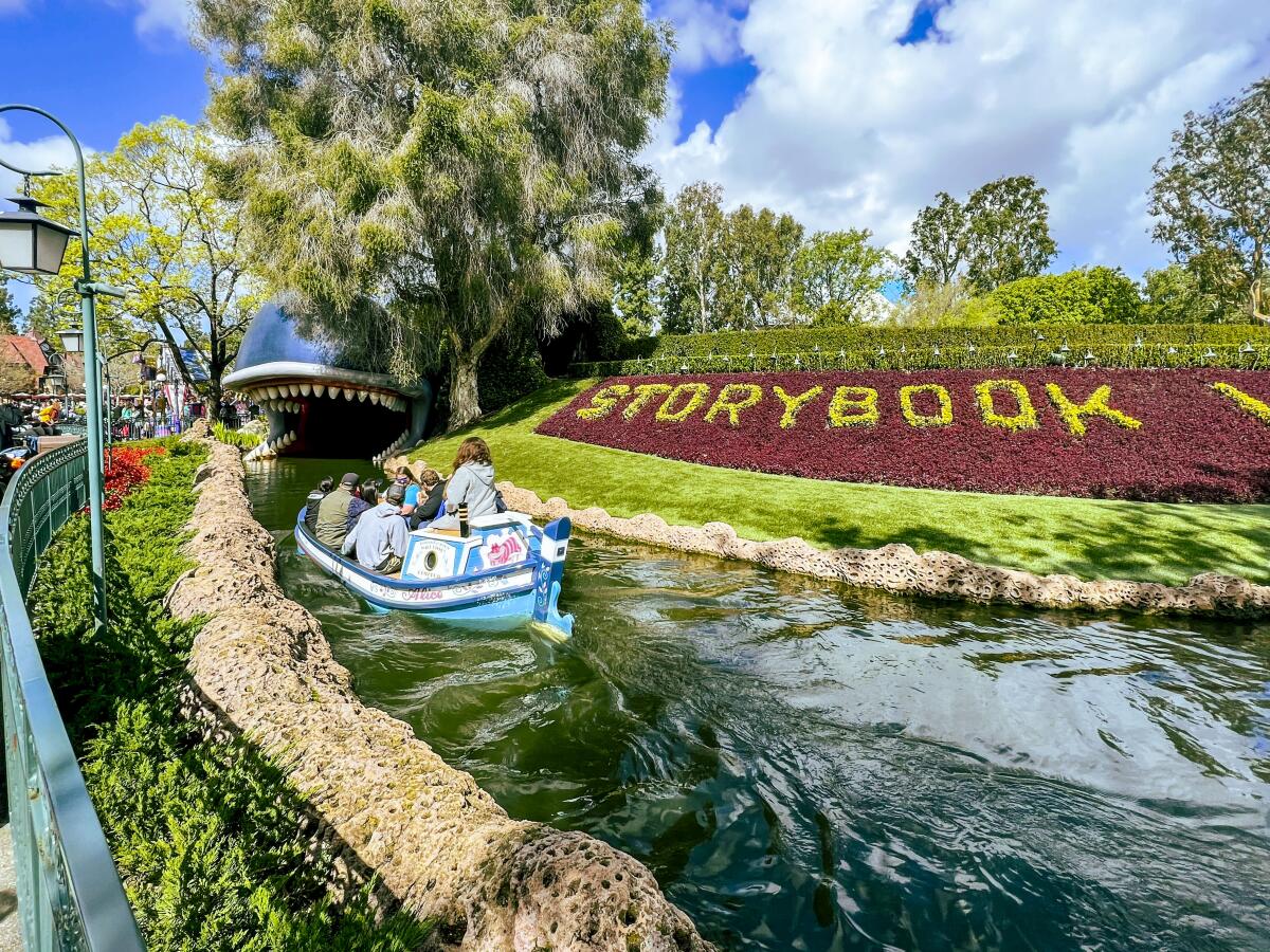 Barcos de canal que llevan a los pasajeros a través de las tranquilas aguas de Disneyland, sobre tierra.