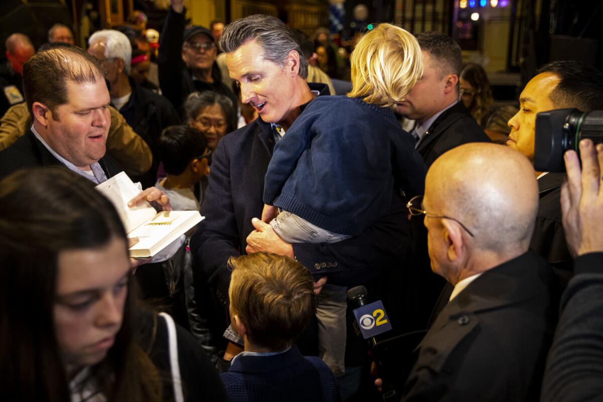 Gov.-elect Gavin Newsom holds his son, Dutch, as he and his family attend an inaugural event at the at the state Railroad Museum Sunday.