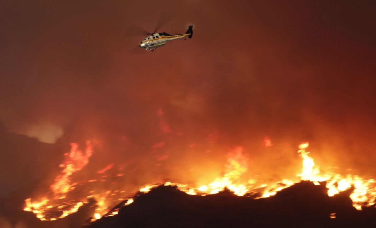 A helicopter flies near the Colby fire burning in the Angeles National Forest.