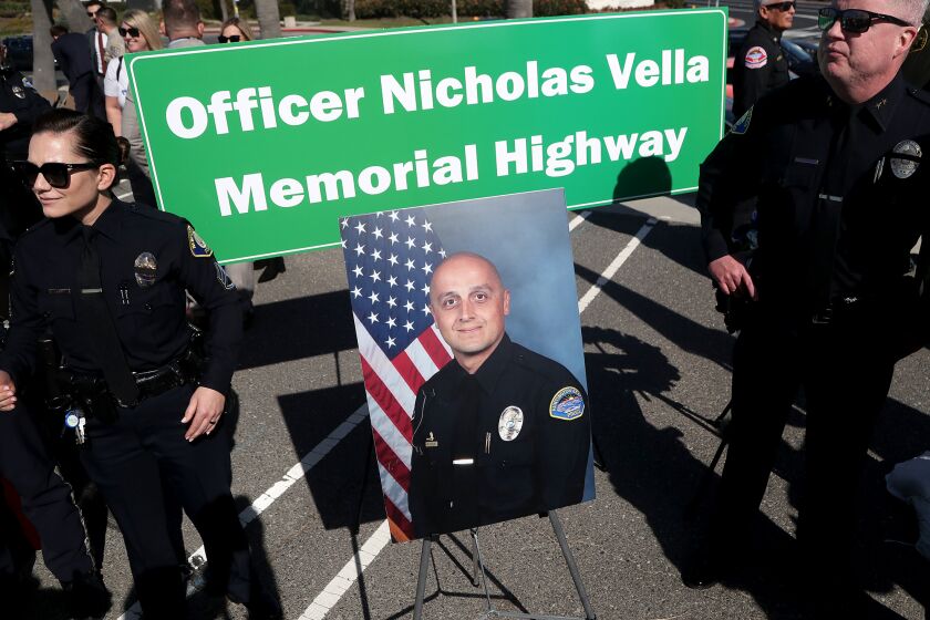 A memorial highway sign stands behind a portrait of Officer Nicholas Vella during an unveiling ceremony for his memorial highway sign on Saturday in Huntington Beach. Vella tragically lost his life in the line of duty on February 19, 2022. He was in a police helicopter (HB-1) and responding to a call for service when it crashed into the waters off Newport Beach. (Kevin Chang / Daily Pilot)