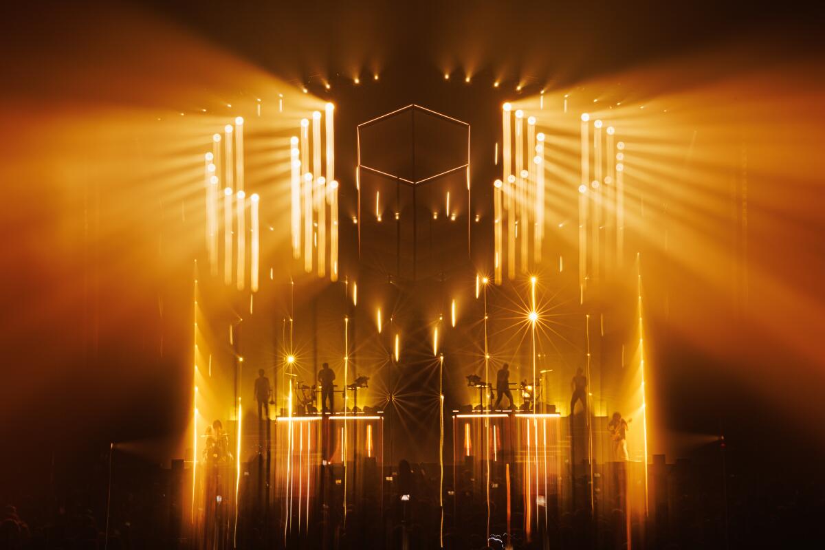 Two DJs performing on platform stages surrounded by gold lighting