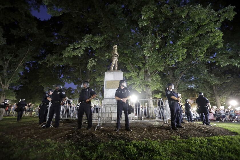 FILE - In this Aug. 22, 2017 file photo, police surround the "Silent Sam" Confederate monument during a protest to remove the statue at the University of North Carolina in Chapel Hill, N.C. The school's board of governors violated the state's open meetings laws by secretly negotiating and approving a deal to dispose of the Confederate monument from the campus of the system's flagship school, according to a lawsuit filed by a student newspaper, news outlets reported on Wednesday, Jan. 8, 2020. (AP Photo/Gerry Broome, File)