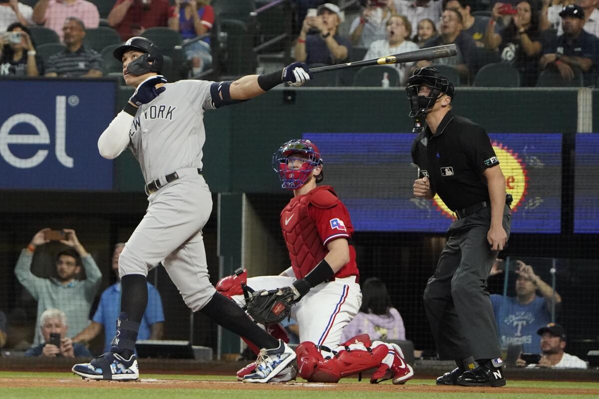 New York Yankees' Aaron Judge hits a solo home in front of Texas Rangers catcher Sam Huff and home plate umpire Chris Segal.