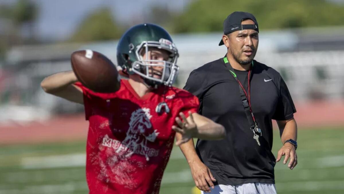 David Gutierrez, right, shown coaching at Costa Mesa in 2018, has been hired as Fountain Valley High School football coach.