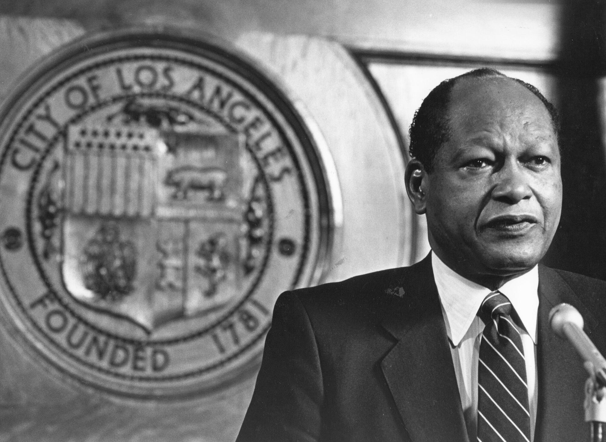 Mayor Tom Bradley stands in from of the Los Angeles city seal