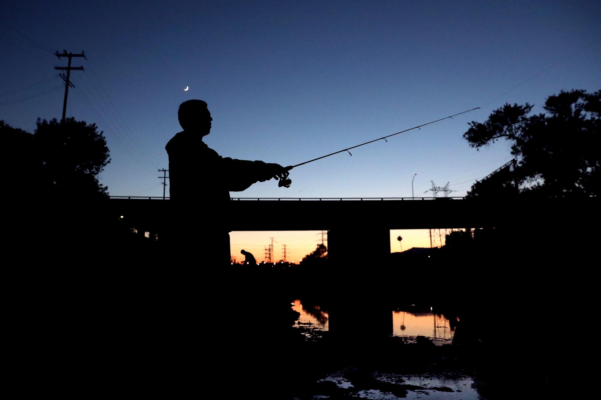 Alvarez, castging into the river, is silhouetted as the sun sets 