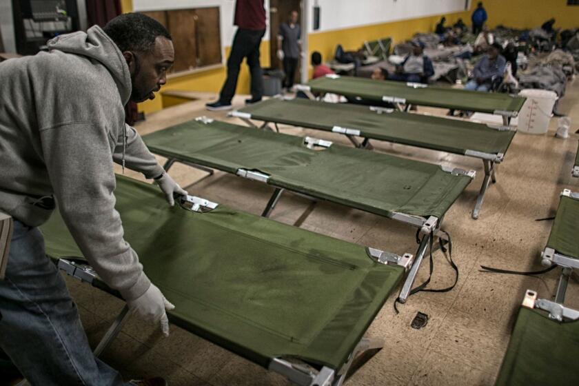 LOS ANGELES, CA, MONDAY, MARCH 20, 2017 - Jeffrey Robinson unfolds dozens of cots in preparation for nightfall at the winter homeless shelter at Bethel A.M.E. Church in South Los Angeles. The shelter's funding ends for the year at the end of March. Its regular turnout of about 115 is now down to the low 80s as men disperse to other locations. (Robert Gauthier/Los Angeles Times)