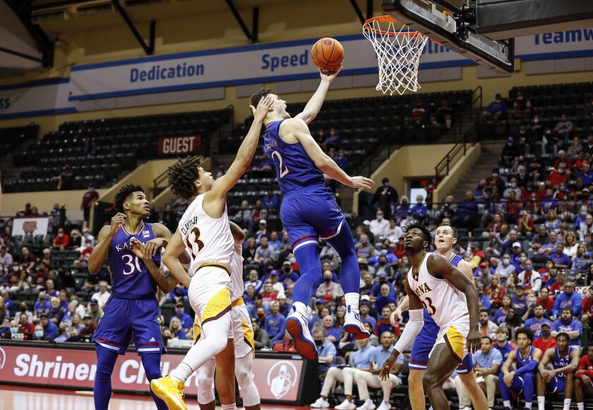 Kansas guard Christian Braun lays up the ball between Iona guard Walter Clayton Jr., front left, and forward Nelly Junior Joseph, front right, during the second half of an NCAA college basketball game Sunday, Nov. 28, 2021, in Lake Buena Vista, Fla. (AP Photo/Jacob M. Langston)