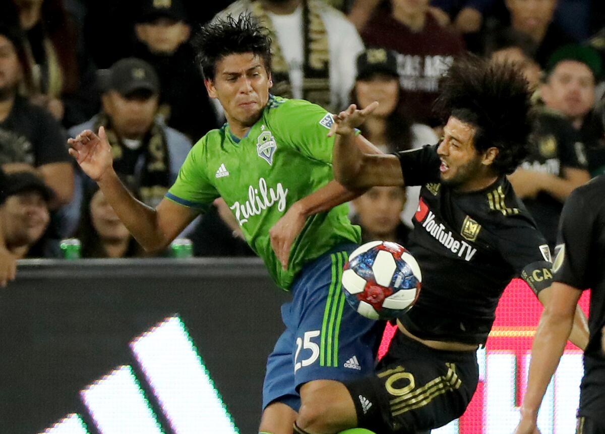 LAFC star Carlos Vela, right, battles Seattle's Xavier Arreaga for control of the ball.