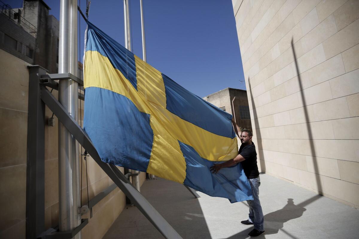 A Palestinian worker fixes the Swedish national flag at the Consulate General of Sweden in Jerusalem on Oct. 5.