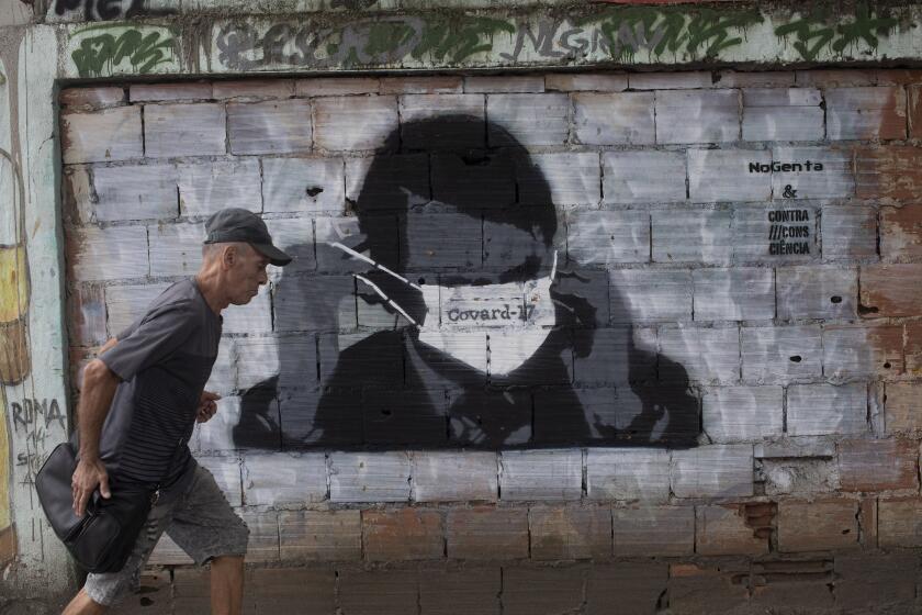 A man walks past a graffiti of Brazil's President Jair Bolsonaro wearing a protective mask during the new coronavirus outbreak in Rio de Janeiro, Brazil, Tuesday, April 7, 2020. (AP Photo/Silvia Izquierdo)