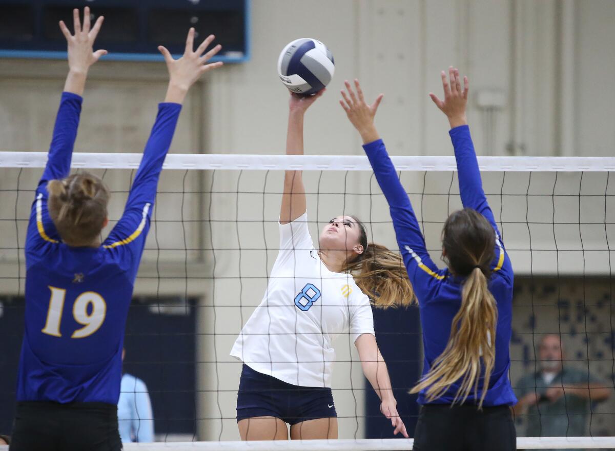 Marina's Abby Magnusen (8) taps the ball over for a point past Zoe Ziegler (19) and Jenna Peterson in a Wave League match against Fountain Valley on Tuesday.