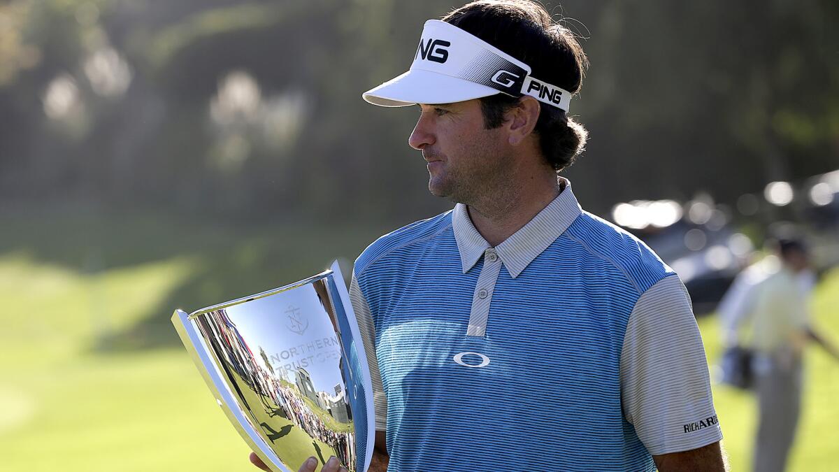 Bubba Watson cradles the winner's trophy on the 18th green after rallying for a victory in the Northern Trust Open at Riviera Country Club on Sunday.