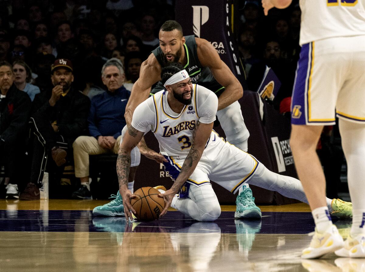 Lakers forward Anthony Davis loses his balance driving to the basket in front of Minnesota Timberwolves center Rudy Gobert.