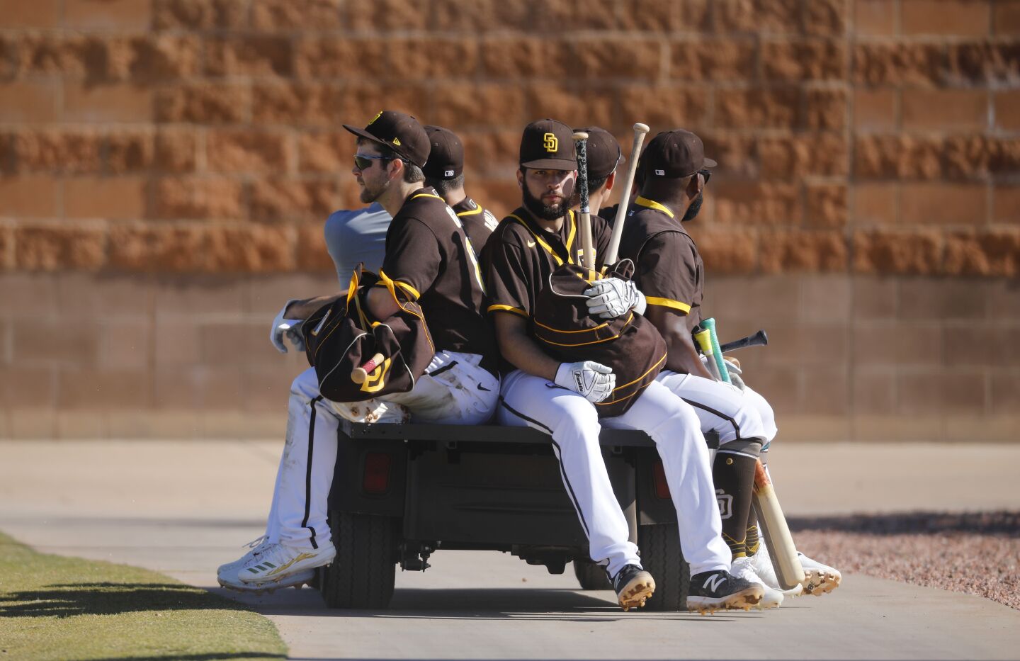 San Diego Padres players ride on a golf cart to a field during a spring training practice on Feb. 20, 2020.