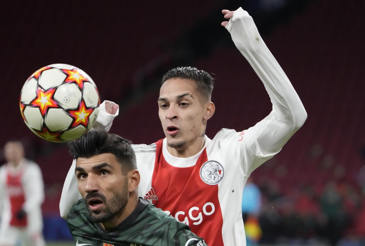 FILE - Sporting's Ricardo Esgaio, left, and Ajax's Antony jump for the ball during a Champions League group C soccer match between Ajax and Sporting CP, at the at the Johan Cruyff ArenA in Amsterdam, Netherlands, on Dec. 7, 2021. Brazil winger Antony looks set to complete a move to Manchester United for $95 million and join Lisandro Martinez in making a big-money switch from Dutch club Ajax to the English giant in this transfer window. (AP Photo/Peter Dejong, File)