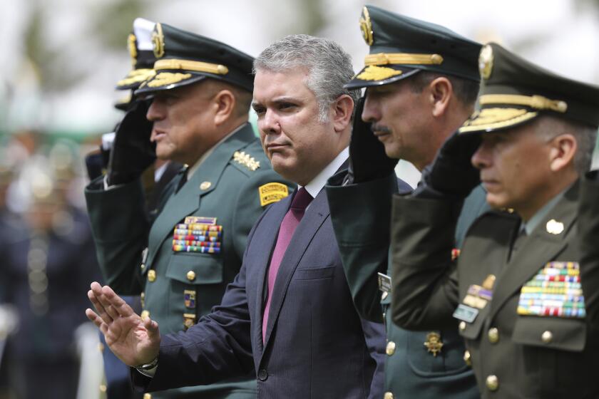 FILE - In this Nov. 7, 2019 file photo, Colombia's President Ivan Duque waves to police cadets, accompanied by his interim Defense Minister and Armed Forces Commander Gen. Luis Fernando Navarro, left, during a graduation ceremony for the cadets in Bogota, Colombia. Labor unions, student groups and ordinary citizens are expected to join in on Thursday, Nov. 21, in what could be one of the nation's biggest demonstrations in recent years, testing the Duque government as unrest grips the region. (AP Photo/Fernando Vergara, File)